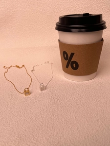 Detail of gold and silver key lock necklaces with white shell inlay on a textured wall
