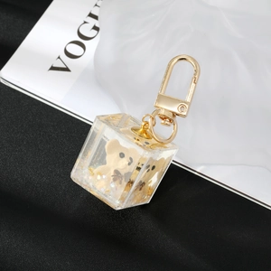 Detail of a clear resin cube keychain with a cute bear and gold foil inside