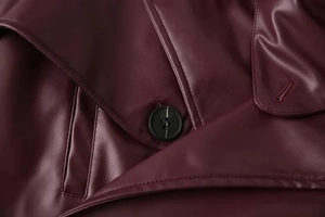 Close-up of burgundy leather jacket featuring black round buttons and precise stitching