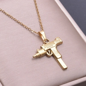 Macro detail of 18k gold plated submachine gun pendant on a champagne jewelry tray