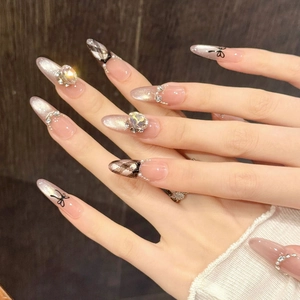 Pink cat-eye press-on nails with luxury crystal accents and hand-painted bows in almond shape
