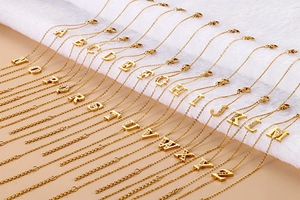 Macro view of gold initial letter charms A-Z with white rhinestones on soft faux fur