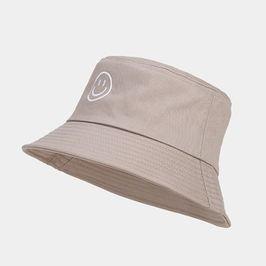 Gros plan d'une broderie smiley blanche sur un chapeau bob beige en toile de coton