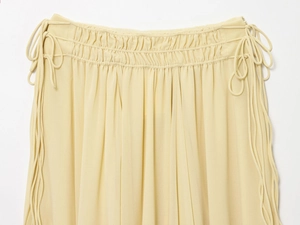 Detailed close-up of elastic ruffled waist and drawstring on pale yellow chiffon skirt
