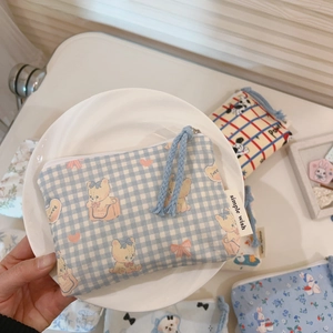 Detail of mini cotton pouches with cartoon prints and decorative zipper pullers