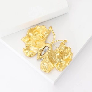 Detailed back view of golden butterfly brooch with water drop gem and pin texture