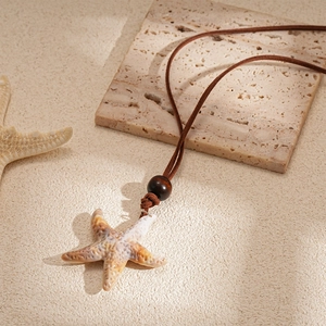 Détail du pendentif étoile de mer avec texture réaliste et perle en bois sur cordon