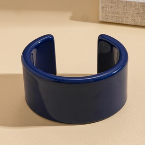 Gros plan du bracelet manchette en résine bleu foncé poli sur texture sablonneuse