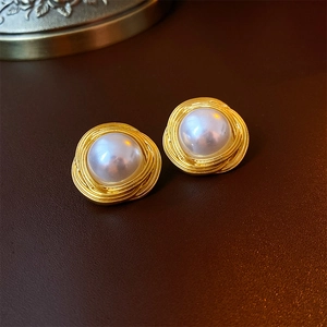Macro d'une boucle d'oreille perle vintage avec base en fil d'or mat sur du cuir