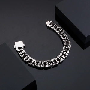 Detail of silver Cuban chain bracelet featuring geometric cutouts and industrial buckle