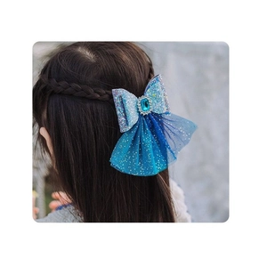 Close-up of blue gradient mesh bow hair clip with sequins and rhinestone on braided hair