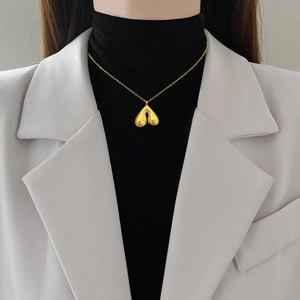 Minimalist gold titanium steel bell pendant necklace for women worn on a beige blazer
