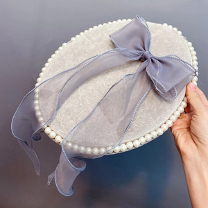 Macro shot of grey velvet jewelry box featuring faux pearl edges and blue organza bow