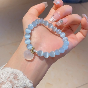 Close-up of blue cat eye stone beaded bracelet with apple jade pendant and pearls