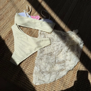 Detailed flat lay of three-piece cream textured bikini set with white floral lace sarong