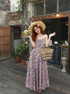 Détail d'une robe fleurie vintage violette avec chapeau de paille et sac à main tissé