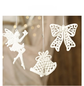 Close-up of white glitter Christmas ornaments featuring fairy, bell, and bow details