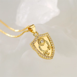 Detail of gold shield pendant with sun, moon, star motifs and sparkling zircon inlay