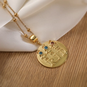 18K gold plated beaded chain necklace with engraved round pendant on white silk fabric