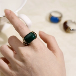 Close-up of elegant gold ring featuring a rectangular green cat eye stone on a hand