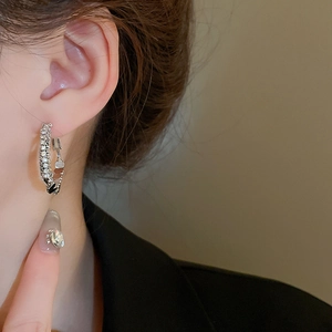 Gros plan de créoles en argent serties de cristaux portées par un mannequin