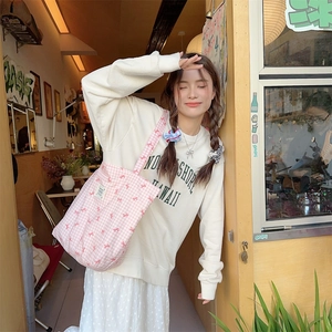 Pink and white checkered canvas tote bag with bow print shown in an outdoor cafe setting