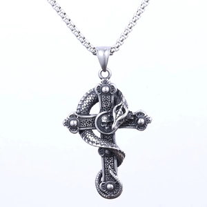 Detail of gothic silver cross pendant with coiled snake and skull relief carving