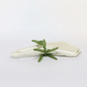 Close-up of Norfolk pine artificial needle ring with beige satin fabric napkin decoration