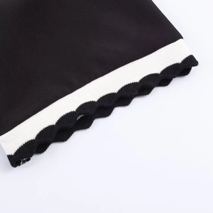 Détail du tissu noir avec ourlet en tricot rayé noir et blanc et coutures précises