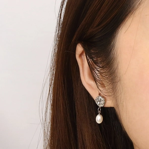 Gros plan sur les boucles d'oreilles irrégulières en métal argenté avec perles blanches