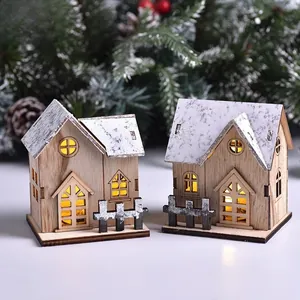Close-up of LED wooden Christmas houses with snowy roofs and warm glowing windows