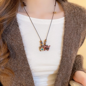 Detailed close-up of a retro camera and cat pendant necklace with a blue gemstone accent