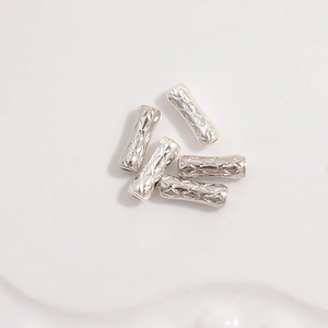 Detailed view of five silver-toned S925 textured metal tube beads for jewelry making