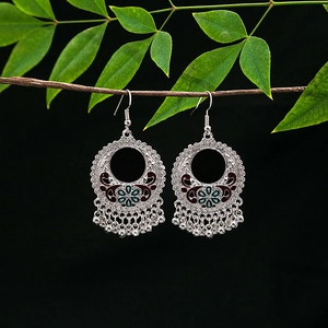 Detail of vintage bohemian earrings with enamel flower pattern and silver ball tassels