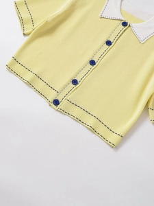 Close-up of yellow knit cardigan with contrast polo collar and black stitching details