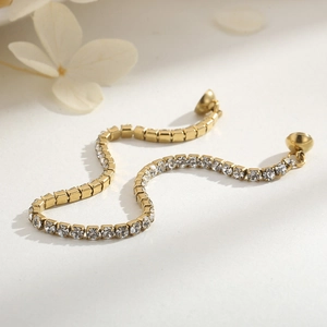 Detailed close-up of gold tennis bracelet with square zircons on a minimalist background