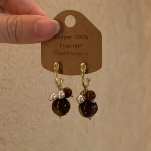 Détail de boucles d'oreilles vintage en résine œil de tigre et perles sur carton