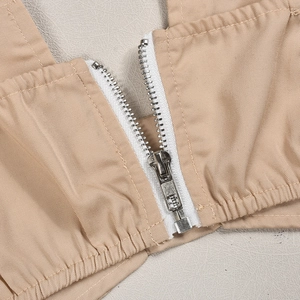 Macro detail of silver metal zipper on khaki twill fabric two-piece set trousers