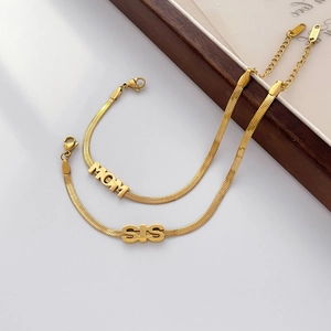 Detail of 18K gold snake chain bracelets with custom MOM and SIS letter pendants
