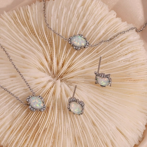 Detailaufnahme von silbernem Opal-Schmuckset mit Kette und Ohrringen auf Korallenbasis