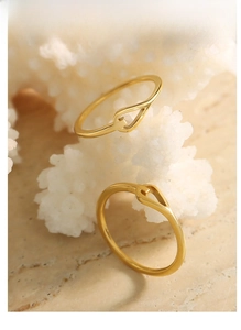 Detailed view of stacked gold cross rings on a luxury marble surface with coral