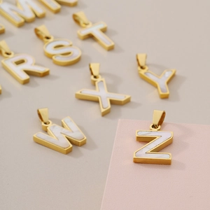 18K gold plated letter pendants with white shell inlay arranged on a geometric background