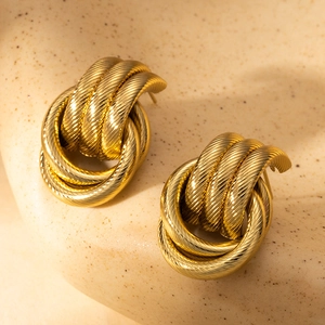 Detailed close-up of golden twist knot stud earrings with elegant ribbed metal texture