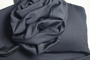 Détail d'une fleur 3D en tissu sur une robe noire en maille à taille haute