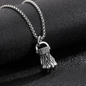Detailed view of silver fist pendant with metallic luster on round bead chain necklace