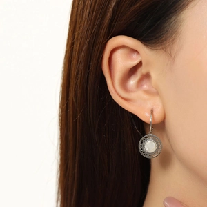 Close-up of silver hoop earrings with white mother of pearl inlay on a model