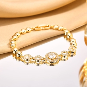 Macro shot of gold-plated bracelet with zircon center and polished beads on silk