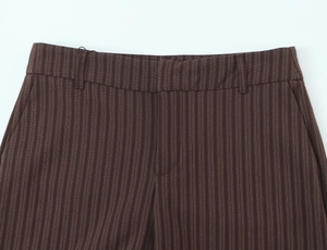 Close-up detail of coffee brown pinstripe trousers showing waist and fabric texture