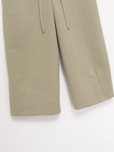 Detail of sage green drawstring waist pants with high-quality knit texture and side slits