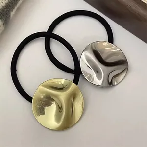 Close-up of gold and silver hammered metal charms on black elastic hair ties